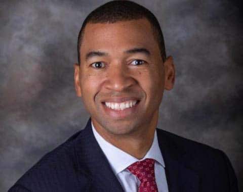 a man wearing a suit and tie smiling at the camera a man wearing a suit and tie smiling at the camera