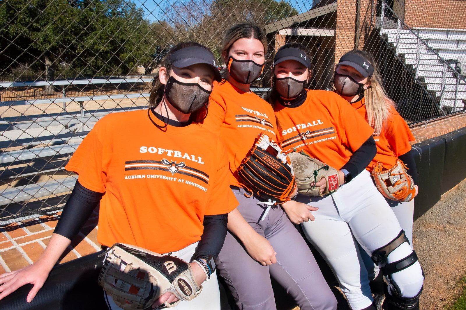 a group of baseball players standing next to a fence