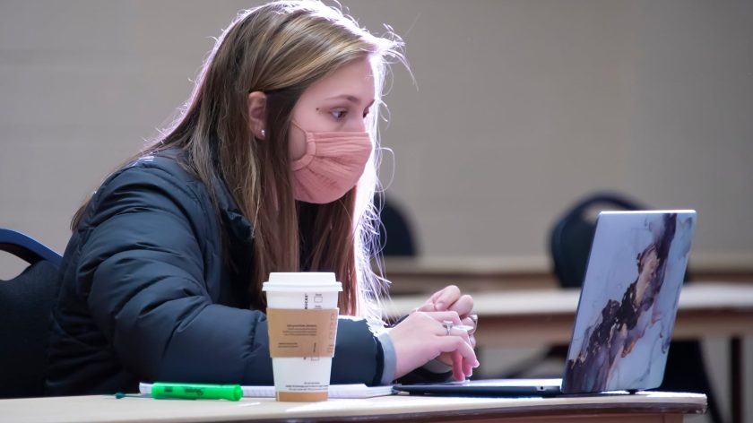 A Woman Sitting At A Table Using A Laptop Computer