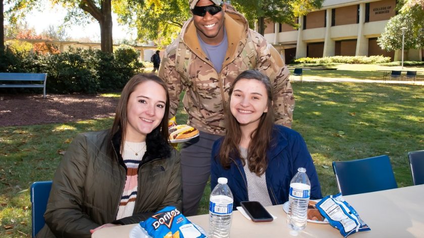 A Group Of People Sitting At A Table Posing For The Camera