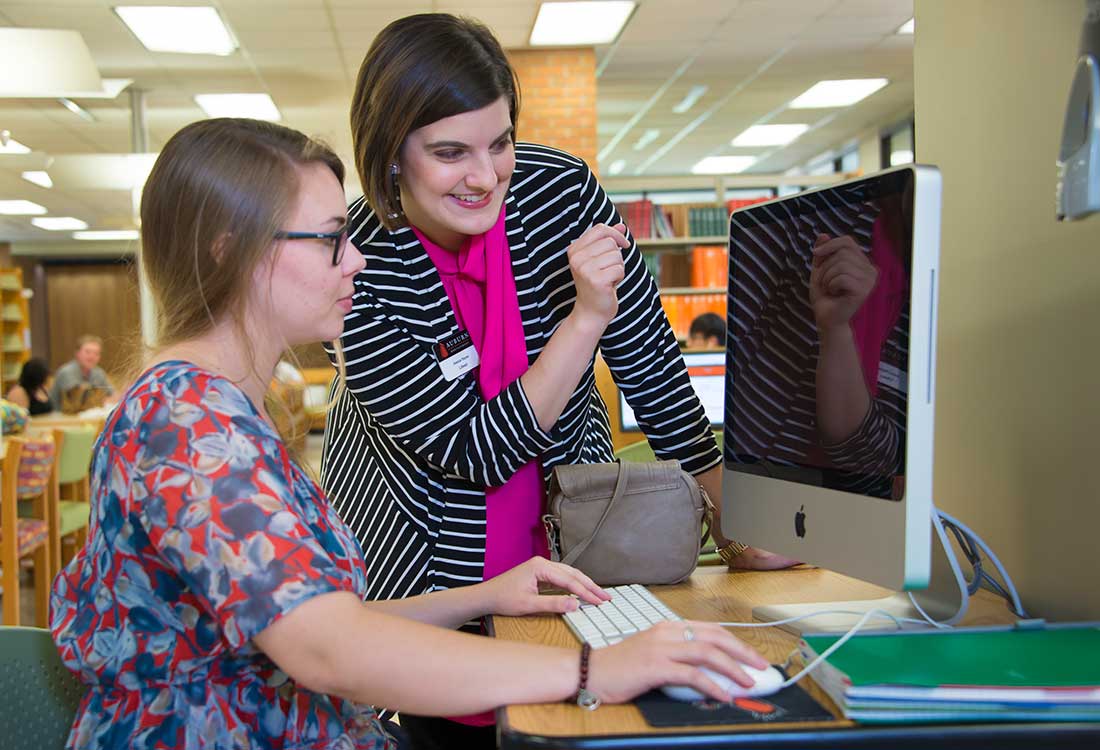 Professor and student working in the library on a project