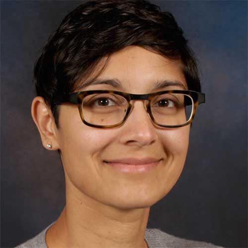 a person wearing glasses and smiling at the camera