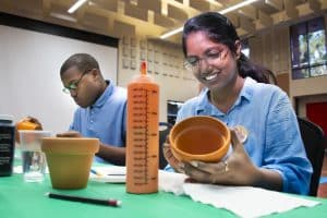 A man and woman paint gardening pots.