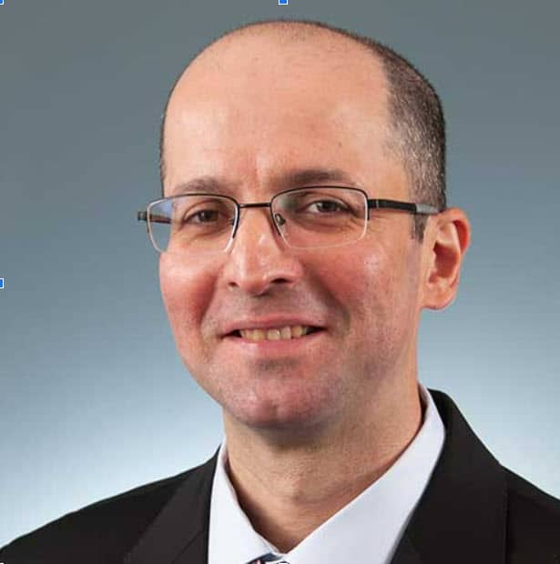 a man wearing a suit and tie smiling at the camera