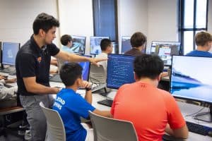 An instructor works with two young learners during one of Auburn University at Montgomery's computer science summer camps.