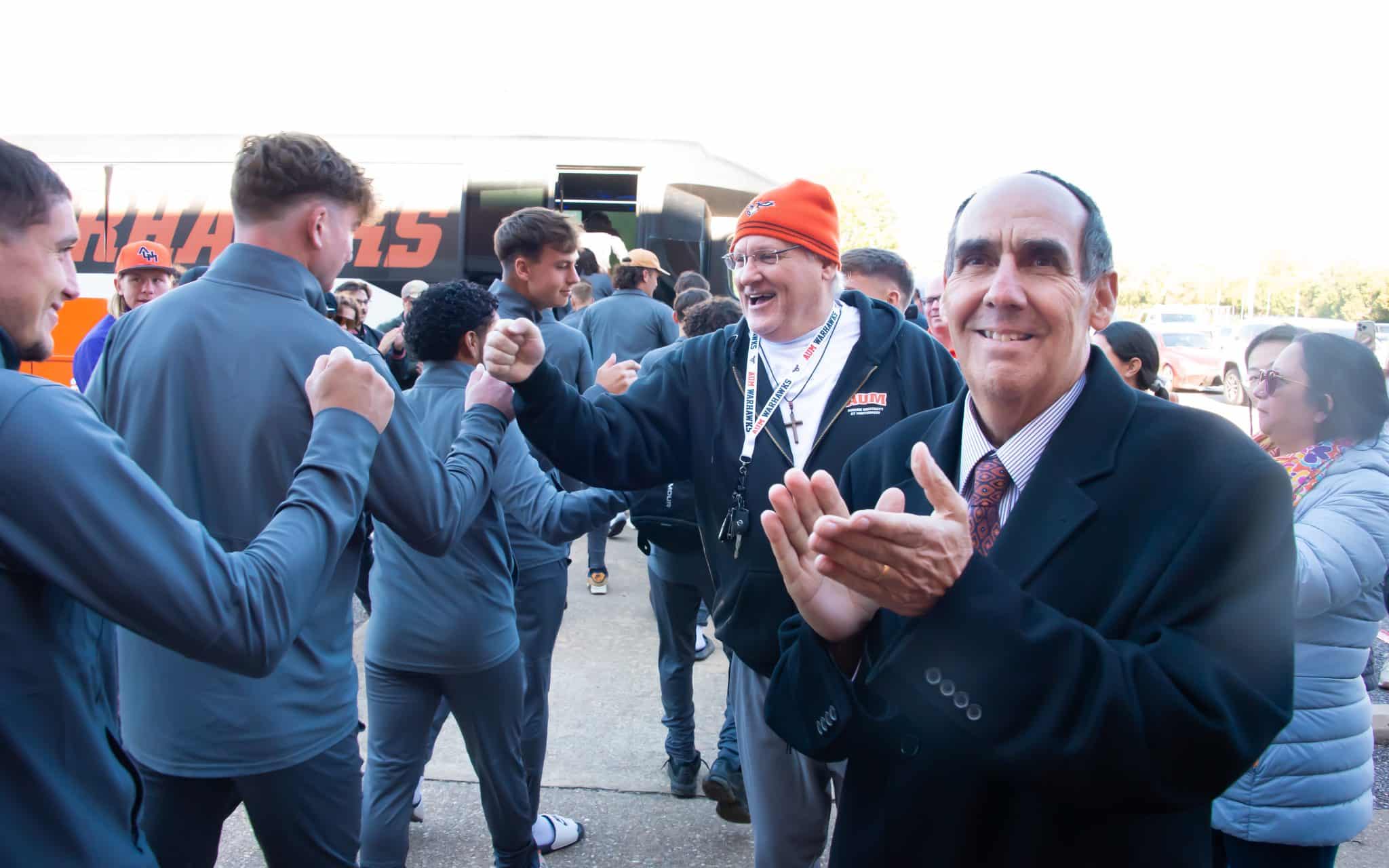 Dr. Carl Stockton cheers for men's soccer as they head off to a match.