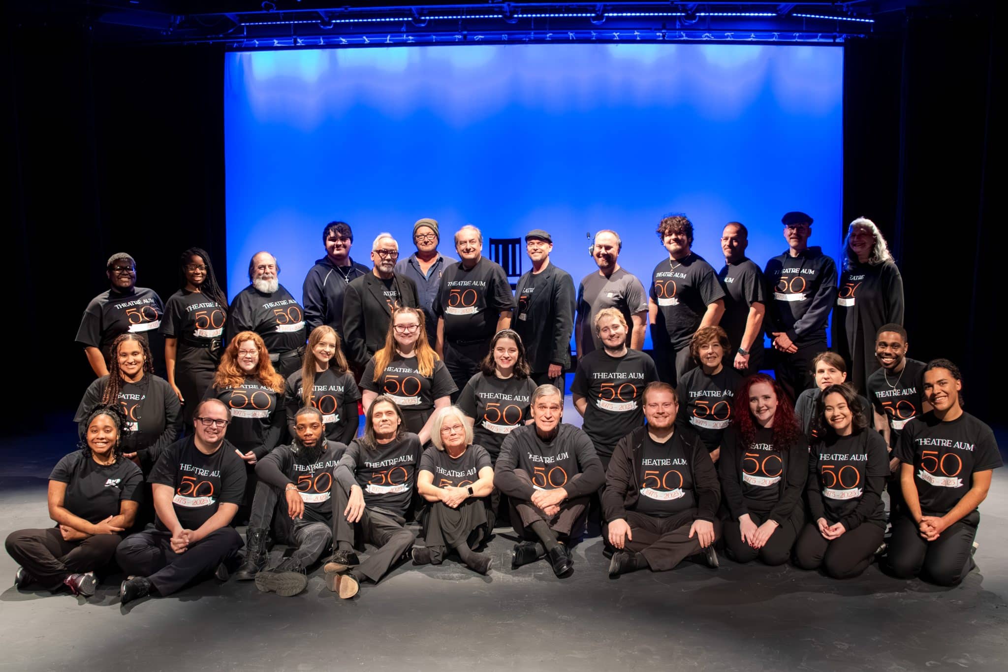 A group of people in Theatre AUM 50 shirts on a stage at Auburn University at Montgomery.