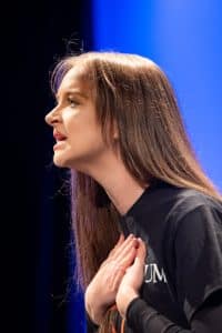 A Woman Passionately Performs On Stage At Auburn University At Montgomery With A Blue Spotlight.