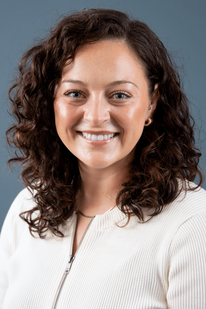A woman with curly hair smiles confidently against a neutral backdrop, representing Auburn University at Montgomery.