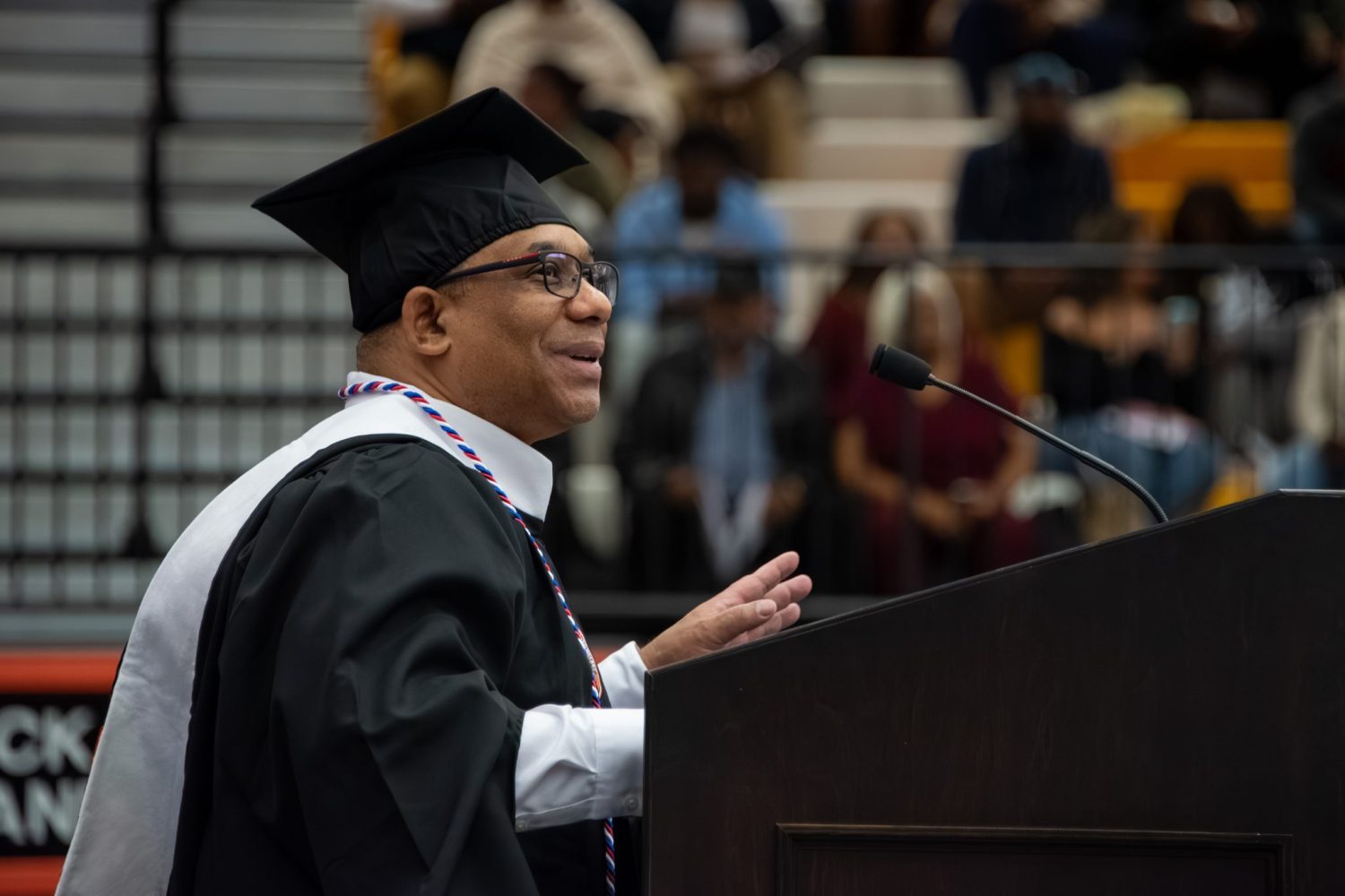 A Graduate In Cap And Gown Speaks At A Podium During Auburn University At Montgomery's Commencement.