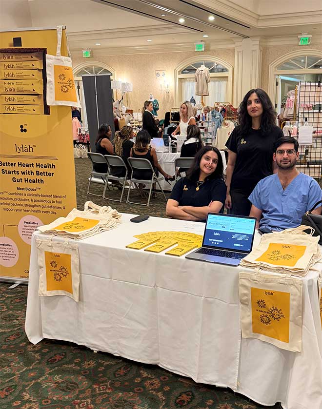 Three people at an informational booth promoting better gut health products.