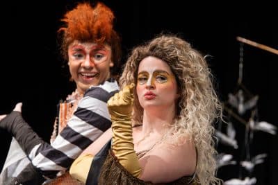 Two performers in vibrant costumes and theatrical makeup on stage at Auburn University at Montgomery.