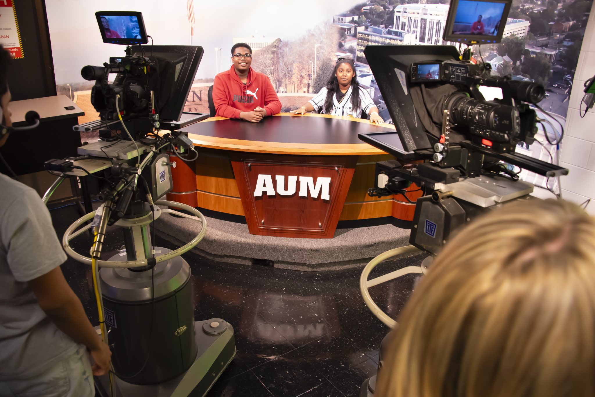 Auburn University at Montgomery students host a broadcast at the AUM news desk with studio cameras during media production