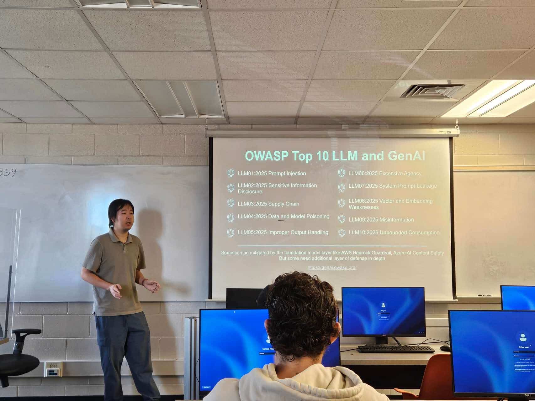 Auburn University at Montgomery classroom lecture on OWASP Top 10 LLM and GenAI, a person presenting to students with screens