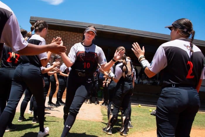 Softball cheers on their teammates as they run onto the field.